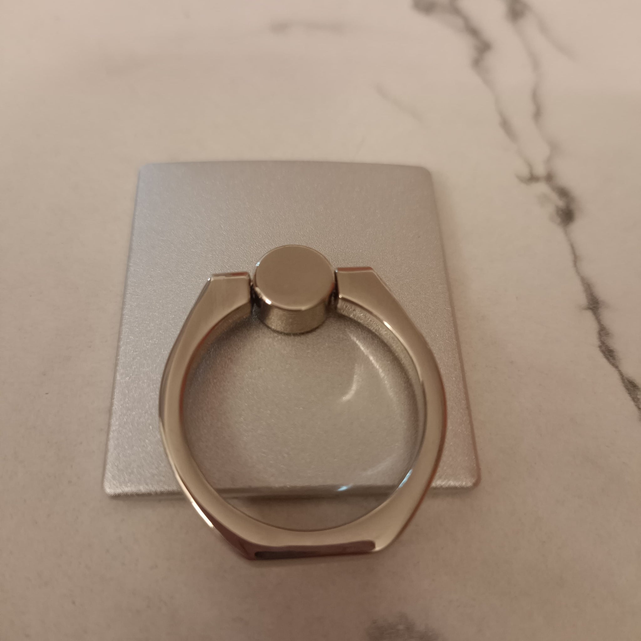 A 360° rotating phone ring holder attached to the back of a smartphone, offering a secure grip and functioning as a stand for hands-free use. Compatible with all smartphone models.